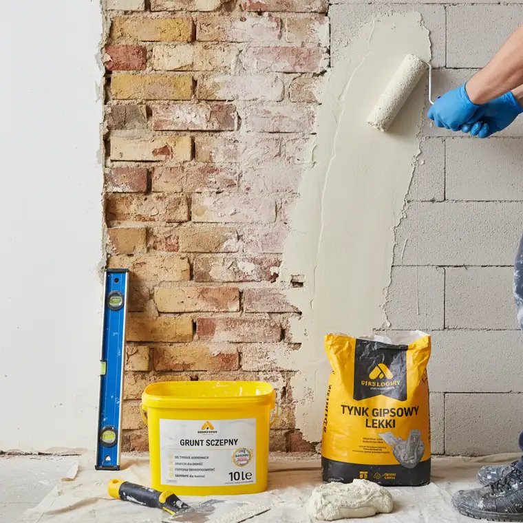 Zbliżenie na ścianę po zagruntowaniu, przygotowanie pod tynk gipsowy – różne marki gruntu i tynku, przykład właściwego doboru materiałów