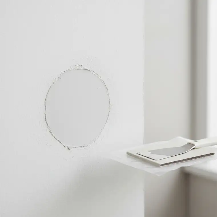 Zbliżenie ściany z punktowo odspojonym tynkiem gipsowym na 1 m² podczas diagnozy i przygotowania naprawy krok po kroku